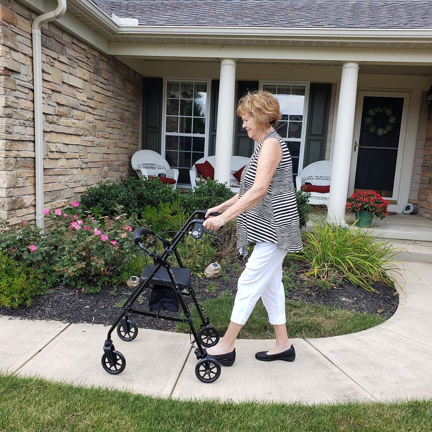 Woman using a walker outside a house with flowers and chairs in the background